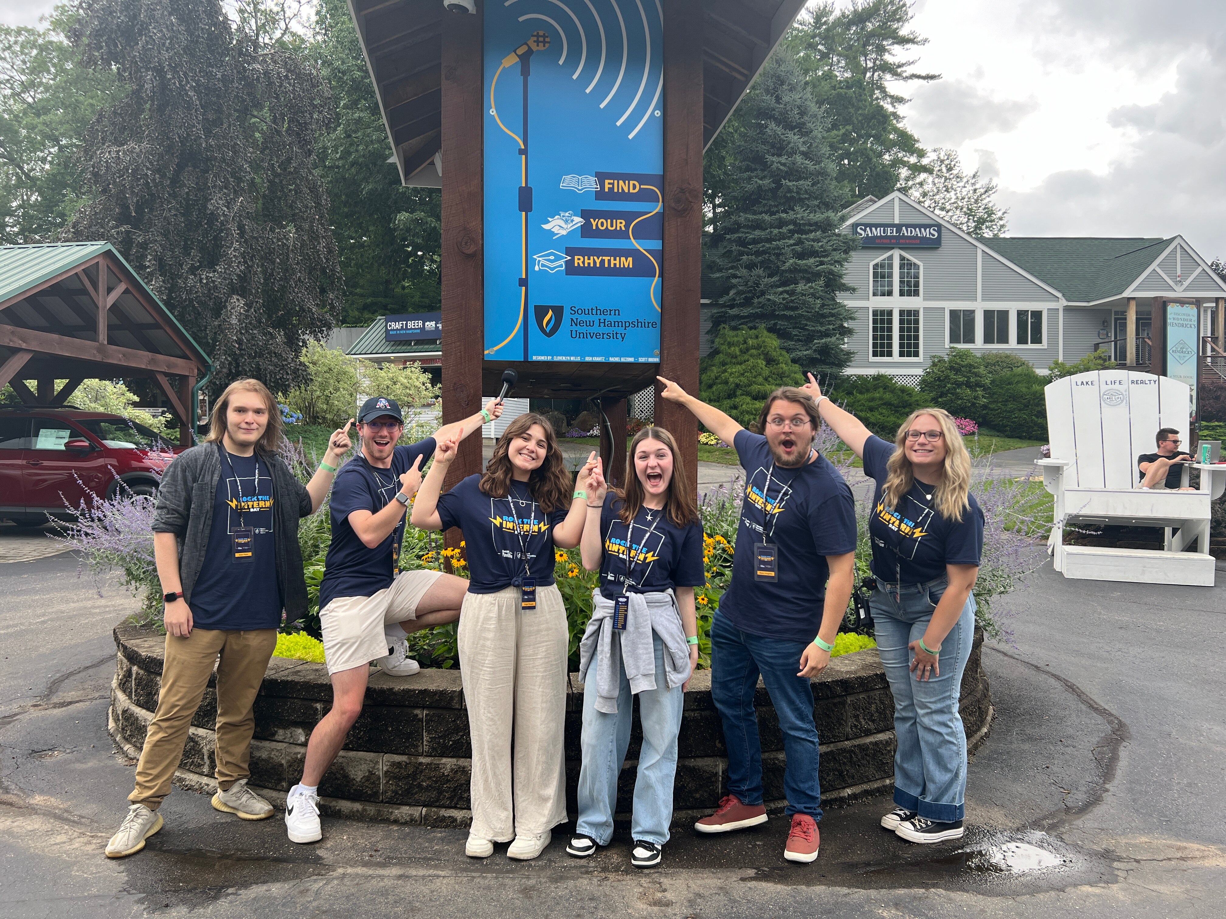 SNHU students standing in front of a Rock the Intern event poster.